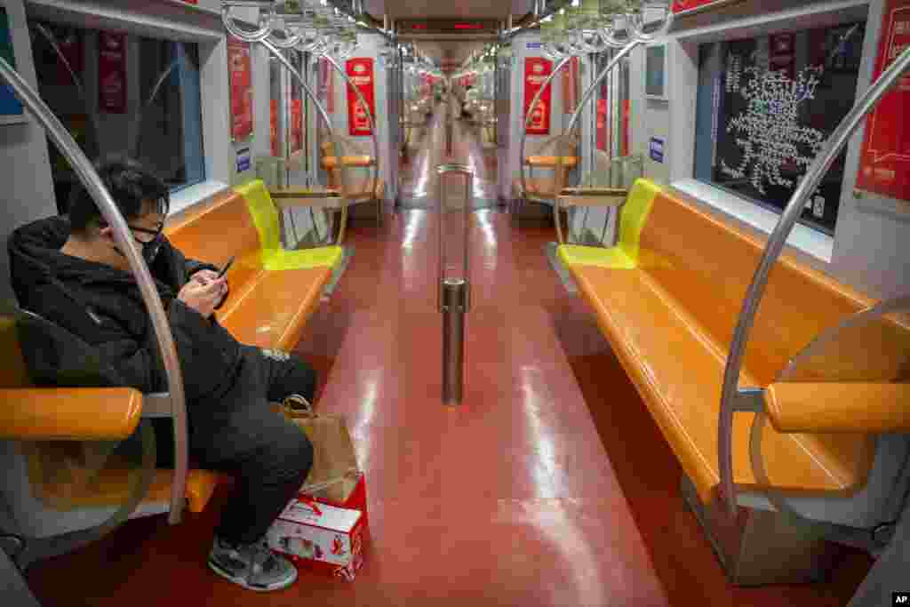 A man wearing a face mask rides a nearly empty subway train in Beijing, China.