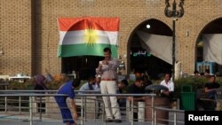 FILE - A man takes a photo of his son near the castle market of Erbil, Iraq, Aug. 17, 2017. 