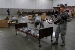 Members of the military assemble some of the beds, April 1, 2020, for use at TCF Center in Detroit to accommodate an overflow of patients with the coronavirus.