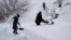 Susan Iannuzzi, left, and Linda Marzell clear a sidewalk after a heavy snowfall on street in Binghamton, New York.