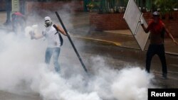 An anti-government protester throws a tear gas canister back at police during a protest against President Nicolas Maduro's government in Caracas, May 8, 2014.