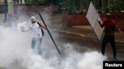 Seorang demonstran anti pemerintah melempar kembali tabung gas air mata ke arah polisi dalam protes anti pemerintahan Presiden Nicolas Maduro di Caracas, 8/5/2014.