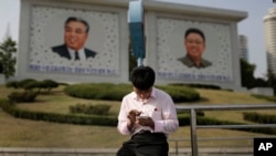북한 평양의 김일성, 김정일 초상화 앞에서 주민이 스마트폰을 사용하고 있다. (자료사진)