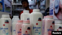 Seorang karyawan toko menunggu konsumen sementara tampak beberapa botol bedak bayi Johnson & Johnson dipajang di sebuah apotek di Kolkata, India, 20 Desember 2018.