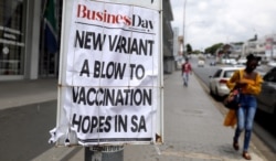 FILE - A woman walks past newspaper billboards during the coronavirus disease (COVID-19) outbreak in Johannesburg, South Africa, Feb. 8, 2021.