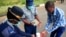 Police officer shows a visitor how to disinfect his hands against the spread of coronavirus disease (COVID-19) at State House in Harare, Zimbabwe, March 19, 2020. REUTERS/Philimon Bulawayo