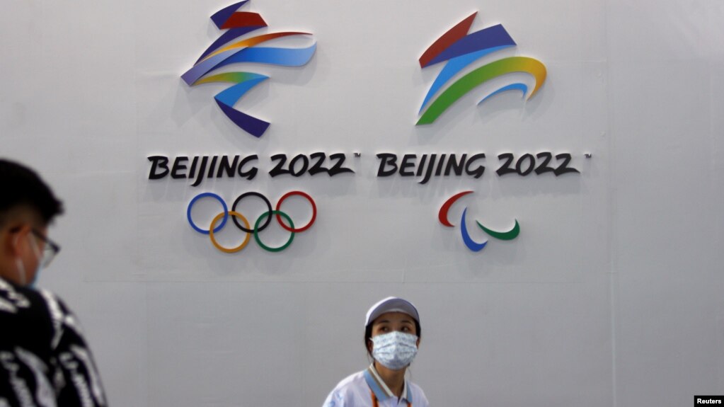 一名戴着口罩的妇女走过北京的国际服务贸易交易会悬挂的2022年冬季奥运会和冬季残奥会标识。（2021年9月3日）
