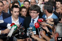 Catalan President Carles Puigdemont, center, speaks to the media at a sports arena designated a polling station by the Catalan government, in Sant Julia de Ramis, near Girona, Spain, Oct. 1, 2017.