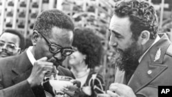 Fidel Castro montre à un leader du parti MPLA Agostinho Neto comment boire un daikiri, une boisson glacée cubaine, à La Havane, le 28 juillet 1976.