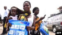 A woman carrying a baby holds a treated mosquito net during a malaria prevention action at Ajah in Eti Osa East district of Lagos, Nigeria, April 21, 2016.