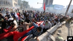 Protesters calling for government reforms run from tear gas fired by Iraqi security forces to disperse the crowd in central Baghdad, Iraq, May 27, 2016.