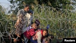 FILE - Syrian migrants cross under a fence into Hungary at the border with Serbia, near Roszke, August 2015.