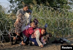 FILE - Syrian migrants cross under a fence into Hungary at the border with Serbia, near Roszke, August 2015.