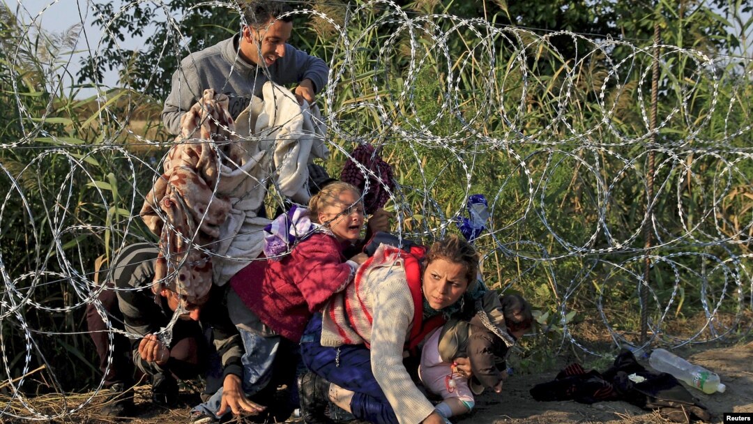Arhiva - Sirijski migranti prelaze preko granice iz Srbije u Mađarsku, ispod žice sa mađarske strane, avgusta 2015.