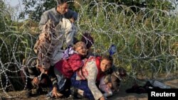 FILE - Syrian migrants cross under a fence into Hungary at the border with Serbia, near Roszke, August 2015.