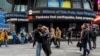 La gente camina por Times Square mientras los teletipos muestran noticias sobre el terremoto del 5 de abril de 2024 en Nueva York.