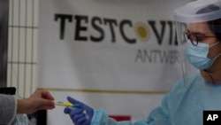 Seorang tenaga kesehatan (kanan) mengambil menerima alat untuk melakukan tes swab di lokasi tes COVID-19 di Antwerp, Belgia, Selasa, 20 Oktober 2020. (Foto: dok).
