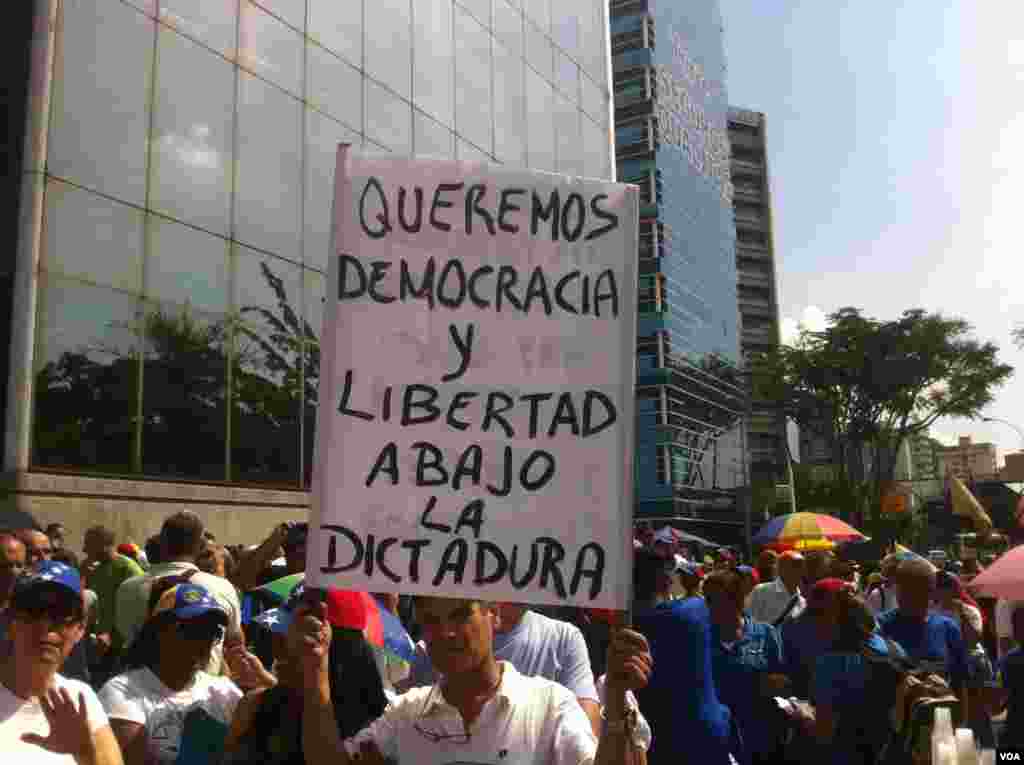 Opposition supporters march in Caracas against Venezuela&#39;s President Nicolas Maduro. Sign reads: &quot;We want democracy and freedom - down with dictatorship.&quot; (A. Algarra/VOA)