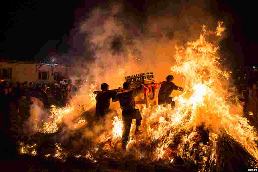 Men carrying a shrine jump over a bon fire during a traditional Chinese lunar new year celebration in Jieyang, Guangdong province, China.