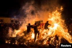 Men carrying a shrine jump over a bon fire, which means a wish for good luck during a traditional Chinese lunar new year celebration in Jieyang, Guangdong province, China, February 2, 2017.