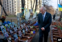 FILE - U.S. Vice President Joe Biden pays his respects at a memorial honoring dozens of demonstrators killed during 2013-1014 anti-government protests in Kyiv, in Ukraine's capital, Dec. 7, 2015.
