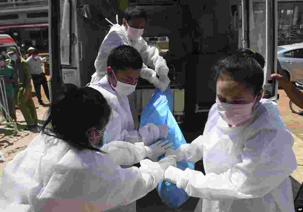 Loatian officials unload the body of a plane crash victim upon arrival at a Chinese temple in Pakse, Laos, Oct. 18, 2013.