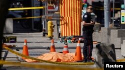 A police officer stands next to a victim of an incident where a van struck multiple people at a major intersection in Toronto's northern suburbs in Toronto, Ontario, Canada, April 23, 2018.