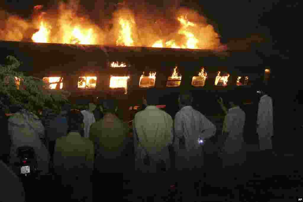 مردم در نزدیکی لاهور پاکستان قطاری را که در آتش می سوزد تماشا می کنند.