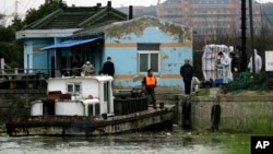 Authorities check the dead pigs, not seen, which have been pulled out from the river on a barge, Mar. 11, 2013, on the outskirts of Shanghai, China. 