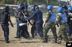 Liberian riot policeman drag away a commander who fired live rounds while storming the compound of the opposition Congress for Democratic Change headquarters in the capital Monrovia, Liberia, November 7, 2011.
