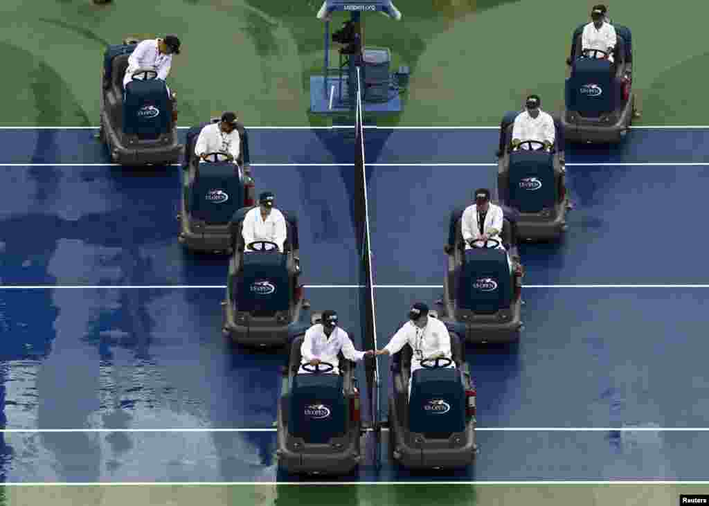 Workers dry the court after a suspension of play due to rain at the 2014 U.S. Open tennis tournament in New York, Aug. 31, 2014.