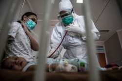 Seorang dokter merawat bayi yang dites positif virus corona Covid-19 di sebuah rumah sakit di Bogor pada 23 Juni 2021, ketika tingkat infeksi di Indonesia melonjak dan rumah sakit kebanjiran pasien baru. (Foto: AFP/Aditya Aji)