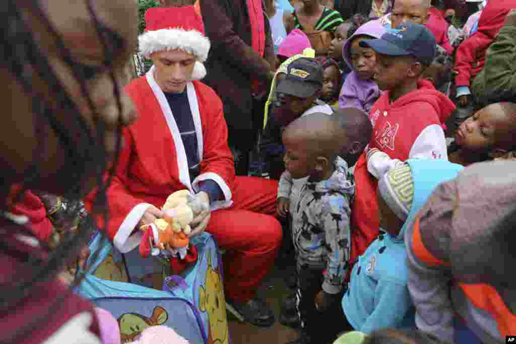 A man dressed as Santa working for a charity distributes gifts to children on Christmas morning in the Joe Slovo squatter settlement near Johannesburg, South Africa, Dec. 25, 2016.