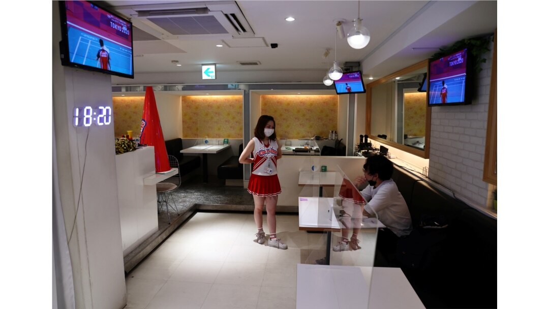Seorang pelayan mengenakan masker di tengah pandemi COVID-19, berbicara dengan seorang pelanggan di bar 'Cheers One' Tokyo, Jepang, yang sepi pengunjung, 29 Juli 2021. (REUTERS/Kim Kyung-Hoon)
