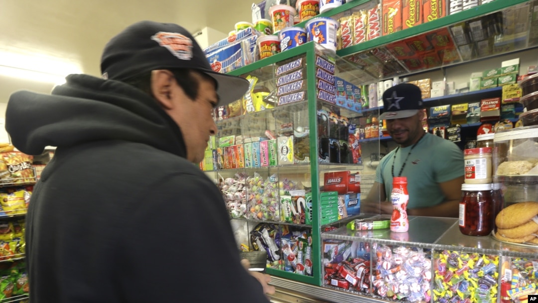 El hijo de Quezada atiende a un cliente en su tienda de comestibles en Nueva Jersey.