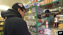 El hijo de Quezada atiende a un cliente en su tienda de comestibles en Nueva Jersey.