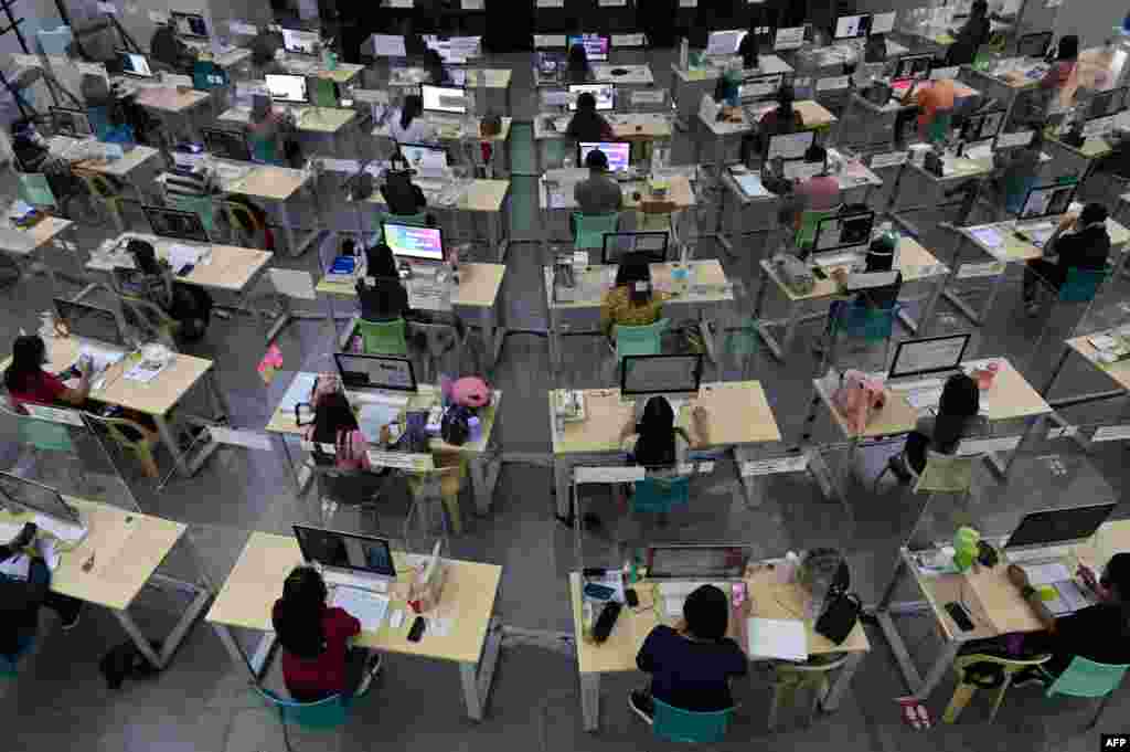 Registered teachers wearing face masks and shields against COVID-19 hold a teleconferencing with students at a local government-sanctioned online class in Taguig City, south of Manila, Philippines.