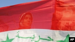 Syrian protesters stand behind a Syrian flag during a demonstration against Syria's President Bashar Al-Assad in front of the Syrian embassy in Amman, July 21, 2011