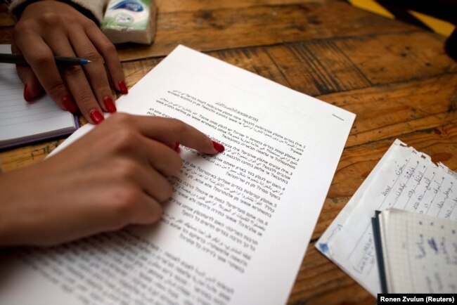 Seorang perempuan membaca kartu prompt yang ditulis dalam bahasa Ibrani dan Arab selama program pertukaran bahasa dengan model kencan kilat, di Yerusalem, 27 Oktober 2021. (Foto: REUTERS/Ronen Zvulun)