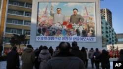 FILE - North Koreans gather in front of a portrait of their late leader Kim Il Sung, left, and Kim Jong Il, right, paying respects to their late leader Kim Jong Il, to mark the third anniversary of his death.