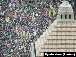 People hold placards and shout slogans as they gather to protest against Japan's Prime Minister Shinzo Abe's security bill outside the parliament in Tokyo, Aug. 30, 2015.