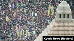 Orang-orang memegang poster dan meneriakkan slogan swat berkumpul untuk memprotes menentang rancangan undang-undang keamanan Perdana Menteri Jepang Shinzo Abe di luar gedung parlemen di Tokyo, 30 Agustus 2015. 