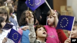 FILE - Bosnian children wave European Union flags at a celebration of European Day in the Bosnian capital Sarajevo, May 9, 2007.