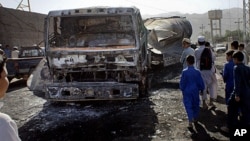 Pakistani youngsters look to a burnt NATO oil tanker caused by alleged militants attacked in Landi Kotal near Afghan border in Pakistan, May 21, 2011