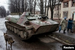 Women walk past destroyed Ukranian army armored personnel carrier (APS) in the town of Debaltseve, north-east from Donetsk, March 13, 2015.
