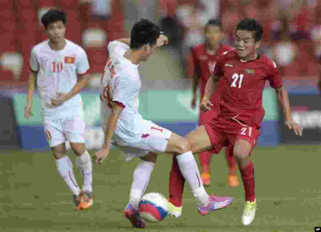 Nguyen Huy Hung of Vietnam, center, and Ko Oo Ye of Myanmar, right, vie for the ball during their soccer semifinal match at the SEA Games in Singapore, Saturday, June 13, 2015. (AP Photo/Joseph Nair)
