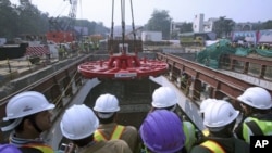 Employees watch as a tunnel boring machine is lowered at a construction site of the Delhi Metro Rail Corporation (DMRC) in Chelmsford Club in New Delhi, January 31, 2012.