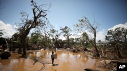 A child walks past debris as flood waters begin to recede in the aftermath of Cyclone Idai, in Buzi near Beira, Mozambique, March 24, 2019.