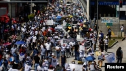La gente participa en una protesta contra las acciones del gobierno del presidente de El Salvador, Nayib Bukele, como el uso de bitcoin y reformas legales para extender su mandato, en San Salvador, El Salvador, el 17 de octubre de 2021.