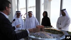 FILE - Rob Lloyd, the CEO of Hyperloop One, left, shows a model to Emirati officials including Mattar al-Tayer, the director-general and chairman of Dubai's Roads & Transport Authority, third left, in Dubai, United Arab Emirates, Nov. 8, 2016.